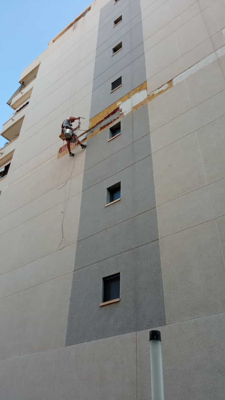Operario de JJ Vertical realizando la rehabilitación de una fachada mediante trabajos verticales en un edificio de Elche.